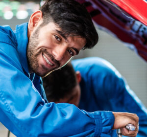 Man looking up from reparing car engine smiling